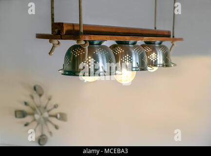 Un éclairage chaleureux qui sortent des lampes à l'intérieur de beaux ustensiles de cuisine, cordes et bois, pendu au plafond horloge murale avec fourches et sp Banque D'Images