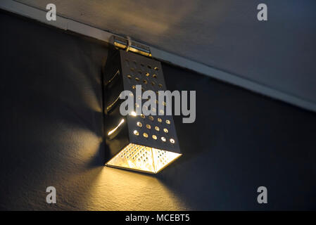 Un éclairage chaleureux qui sort de la belle cuisine maison bricolage lampes et râpe sur mur. Banque D'Images