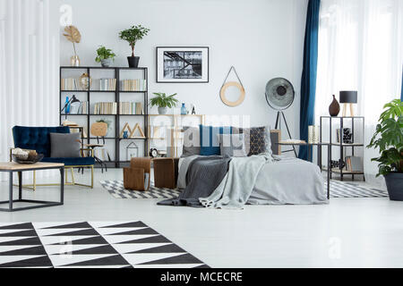 Tapis noir et blanc dans une chambre spacieuse avec un fauteuil d'intérieur bleu marine à côté du lit Banque D'Images