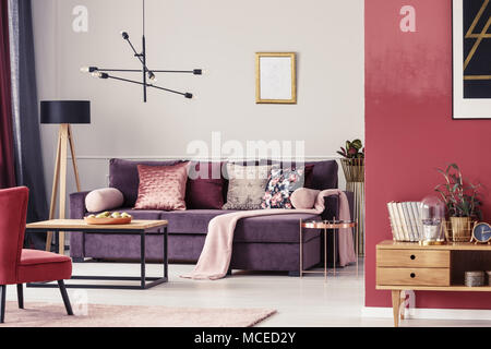 Salon marron intérieur avec canapé ultra violet à motifs, oreillers et cadre doré sur le mur Banque D'Images
