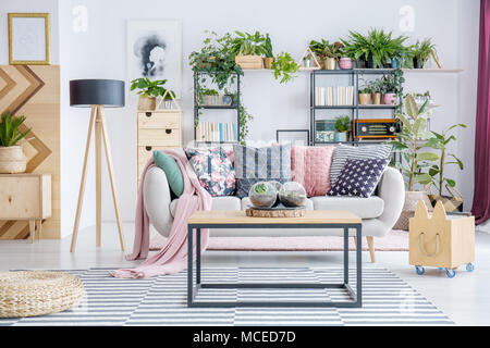 Boules de verre à la main avec des plantes placées sur une table dans un salon intérieur avec lampe et de la table Banque D'Images