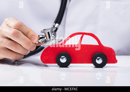 Close-up of a main du médecin l'examen de voiture rouge avec stéthoscope Banque D'Images