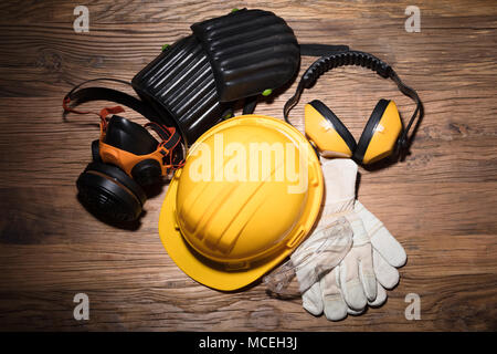 Close-up of Yellow Casque avec équipement de sécurité sur fond de bois Banque D'Images