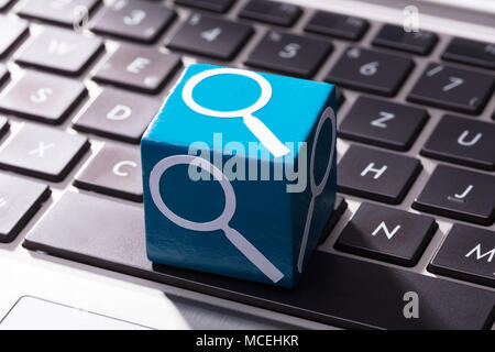 Close-up de Loupe Symbole sur bloc de bois bleu sur le clavier d'ordinateur portable Banque D'Images
