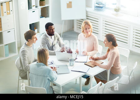 L'équipe multi-ethnique des gestionnaires se sont réunis au bureau spacieux et discuter de projet start-up, high angle view Banque D'Images