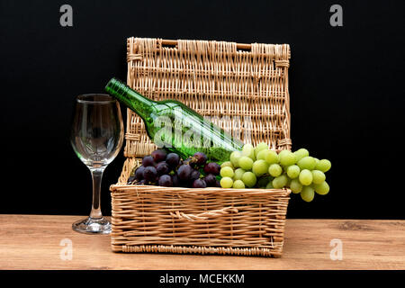La vie encore. Raisin avec un verre et la bouteille dans un panier avec fond noir. Banque D'Images