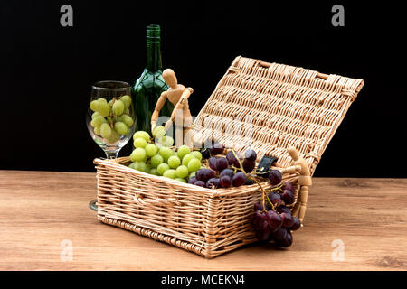 La vie encore. Grappes de raisin dans un panier en osier avec deux mannequins. Banque D'Images