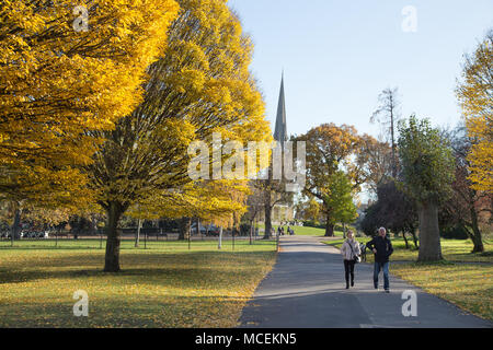 Couleurs d'automne à Clissold Park, Stoke Newington, London N16, avec un vieux couple en train de marcher et le clocher de l'église St Mary à l'arrière-plan Banque D'Images