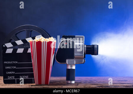 Un appareil photo avec film popcorn et Clapper Board contre fond bleu Banque D'Images