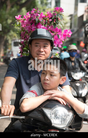 Un père et son fils, porteur d'une usine d'azalées à l'arrière de leur moto à Hanoi, Vietnam, Asie du sud-est Banque D'Images