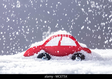 Voiture rouge couverte de neige dans les fortes chutes de neige Banque D'Images