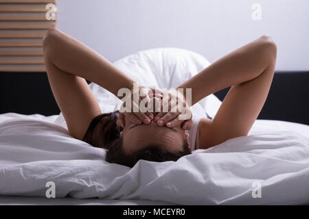 Close-up of a souligné Young Woman Lying On Bed Banque D'Images