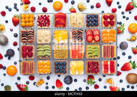 Tartes aux fruits carrés colorés sur une grille de refroidissement sur un fond blanc. Banque D'Images