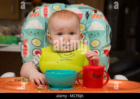 bébé garçon de 12 mois aux cheveux rouges dans une chaise haute manger Banque D'Images