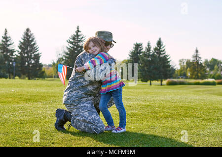 Soldat réunis avec sa fille. Enfant avec usa flag est l'étreindre papa militaire en plein air de l'été parc. Banque D'Images