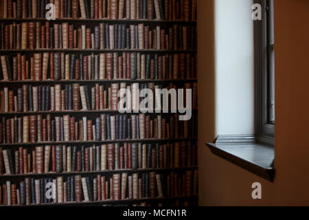 Une chambre avec un mur tapissés de livres à regarder de plus en plus pointues de Portsmouth, Hampshire, Royaume-Uni. Banque D'Images