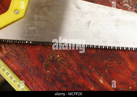 Travail en atelier de menuiserie. Vu et bande de mesure se situent sur workbench sale en atelier de menuiserie. Outils pour travail manuel Banque D'Images