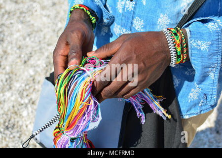 Black Man's qualifiés mains décorées avec bracelet africain traditionnel, plein de couleurs, de chaîne de production de matériel pour bracelet Banque D'Images