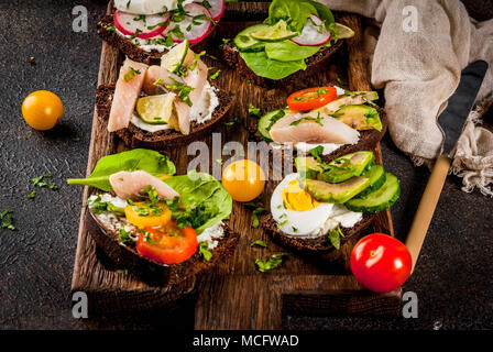 Ensemble de divers sandwiches ouverts Smorrebrod danois avec du poisson, des oeufs et des légumes frais, fond sombre copy space Banque D'Images