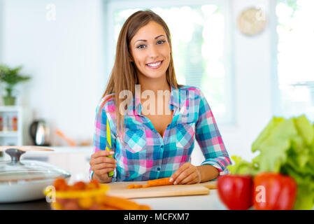 Belle jeune femme faisant des repas dans la cuisine domestique. Elle est à la carotte au conseil de la cuisine. Banque D'Images