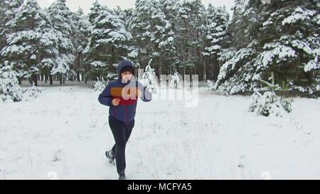 Jeune homme sportif de canal qui traverse la forêt enneigée. shot Vue de face hiver arbre forêt dans la neige Banque D'Images