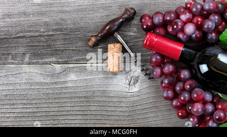 Unopen bouteille de vin rouge et les raisins sur bois vintage Banque D'Images