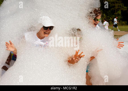 Lawrenceville, GA, USA - 31 mai 2014 : les femmes sourire et rire tout en sortant d'un nuage de mousse savonneuse à Bubble Palooza. Banque D'Images