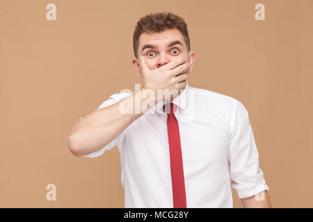 Oh non ! L'homme avec de grands yeux main fermée la bouche. Concept des gens d'affaires, bonnes et mauvaises émotions et sentiments. Studio shot, isolé sur light brown backgroun Banque D'Images