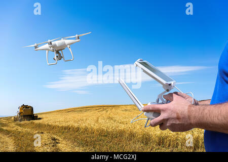 Le contrôle d'un drone hélicoptère à distance. Contrôleur à distance de vol de drone dans l'homme les mains. voler au-dessus de champs Banque D'Images