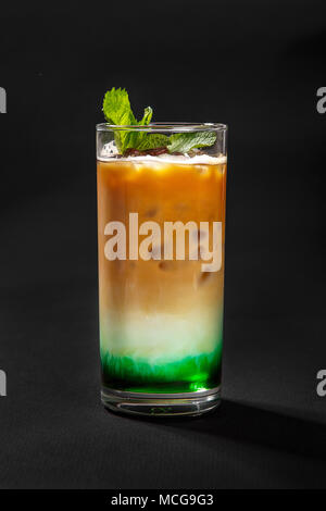 Un multicolores, opaque en trois couches d'un cocktail dans un grand verre de glace pilée et de feuilles de menthe et les grains de café, avec le goût de menthol, café, ca Banque D'Images