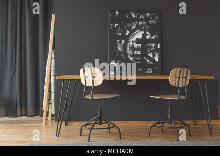 Peinture noir et blanc l'article contre un mur sombre, sur une table à manger en bois à l'intérieur chambre monochromatique Banque D'Images