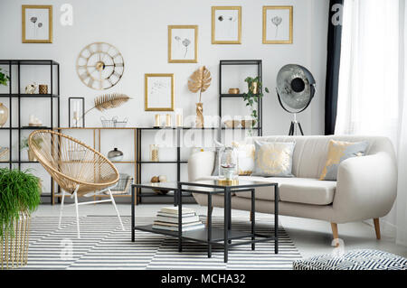 Président de l'or à côté de table noire et beige canapé dans le salon intérieur avec des dessins et de l'horloge Banque D'Images