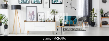 Salon blanc intérieur avec galerie sur le mur, l'armoire en bois et des plantes fraîches Banque D'Images