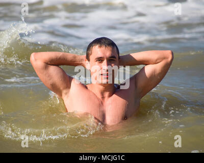 L'homme athlétique dans l'eau de mer. Baignade en mer. Un homme nage parmi les vagues de la mer. Banque D'Images