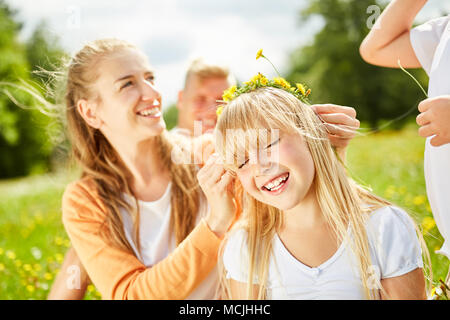 Décore la mère de sa fille de cheveux avec flower wreath au printemps Banque D'Images