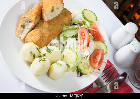 Un pub anglais repas de poulet pané frit et de légumes avec pommes de terre bouillies et rissoles salade mixte Banque D'Images