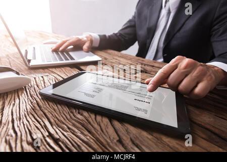 Close-up of a Businessman's Hand Travailler avec facture sur tablette numérique Banque D'Images