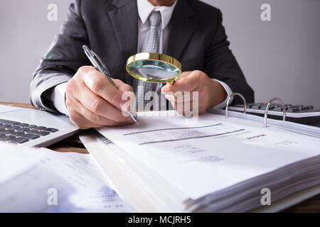 Close-up de la main de l'homme d'affaires à la loupe par les reçus au travail à Banque D'Images