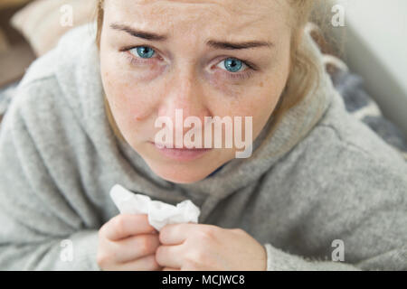 Malade et fatigué femme avec un mal de tête assis sur un canapé de demander de l'aide. Closeup portrait. Banque D'Images