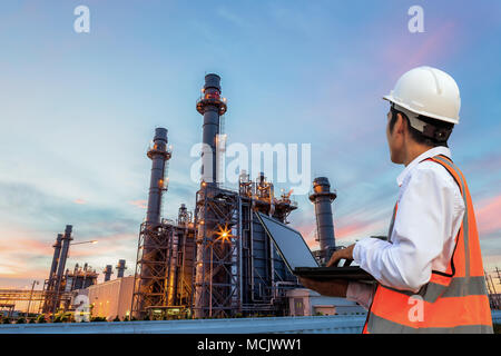 L'ingénierie est utiliser et contrôler l'ordinateur portable en face de la raffinerie de pétrole lourd dans la structure du bâtiment de l'industrie pétrochimique Banque D'Images