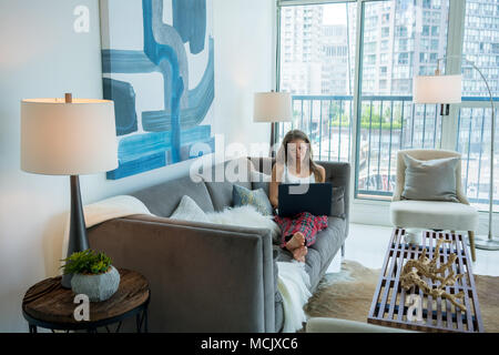 Young woman on sofa in modern living room Banque D'Images