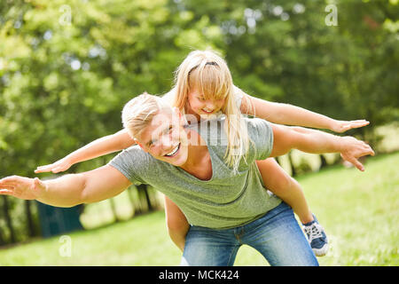 Fille sur le dos de son père tente de garder son équilibre Banque D'Images