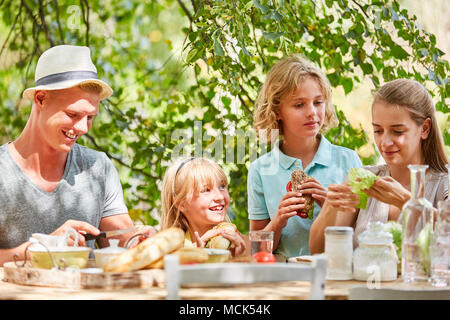 Famille et enfants de prendre le petit déjeuner ou un brunch dans le jardin en été Banque D'Images