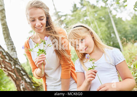 Mère et fille ensemble dans le jardin pendant que la cueillette des fleurs Banque D'Images