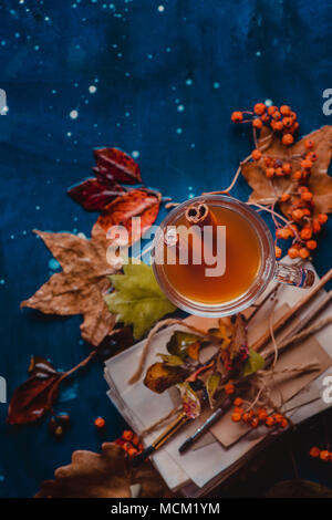 Mise à plat de l'automne avec les feuilles tombées et une pile d'artiste scetches avec brosses de peinture. La vie encore des pluies avec une tasse de thé en verre sur un background en bois humide Banque D'Images