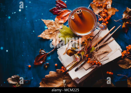 Mise à plat de l'automne avec les feuilles tombées et une pile d'artiste scetches avec brosses de peinture. La vie encore des pluies avec une tasse de thé en verre sur un background en bois humide Banque D'Images