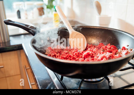 Hachis de boeuf et d'oignons browning off dans un wok sur une cuisinière à domicile. Banque D'Images