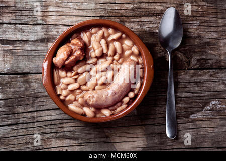 Portrait d'un bol en terre cuite avec un cassoulet de Castelnaudary, un ragoût de haricots typiques de l'Occitanie, en France, sur une table en bois rustique Banque D'Images