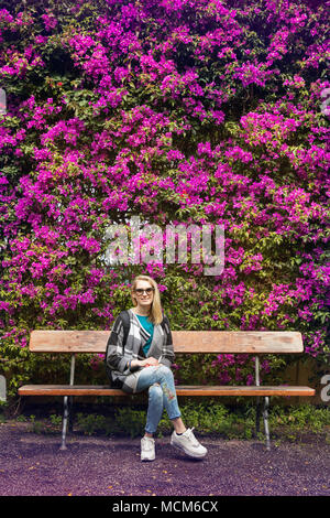 Femme assise sur le banc en face de couverture fleurs de mauve Banque D'Images