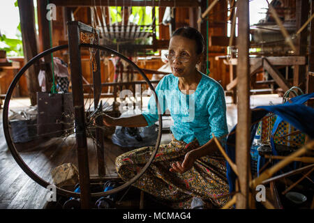 Hauts Femme tissant la soie sur la roue tournante à l'intérieur de maison, l'État de Shan, Myanmar Banque D'Images